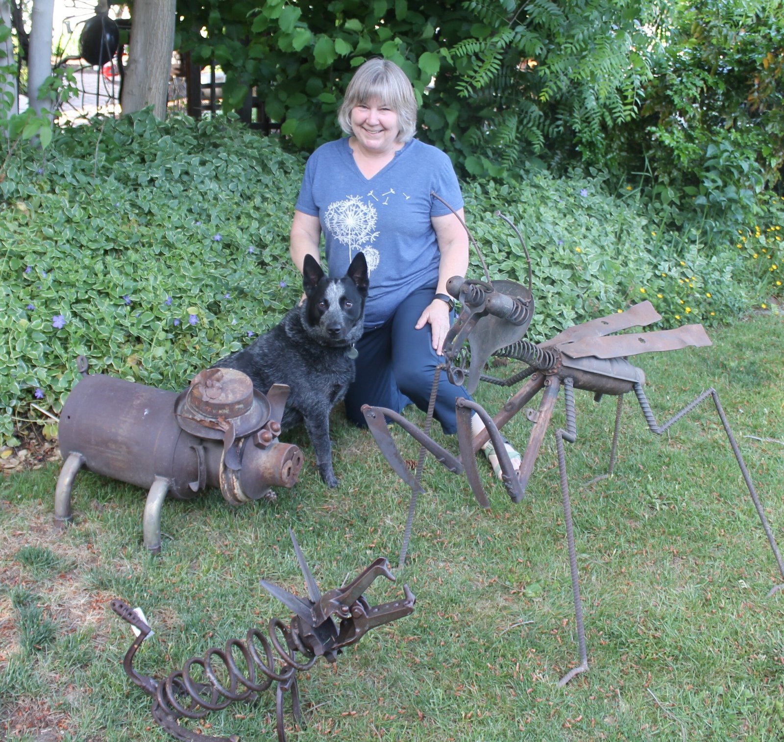 Woman and dog in the garden with metal yard art.
